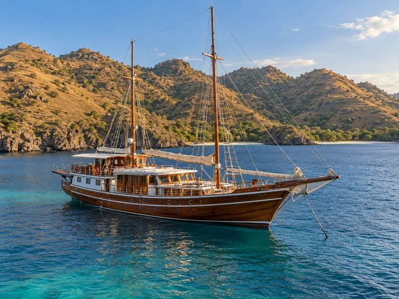 Phinisi boat anchored beside the hills of Komodo National Park
