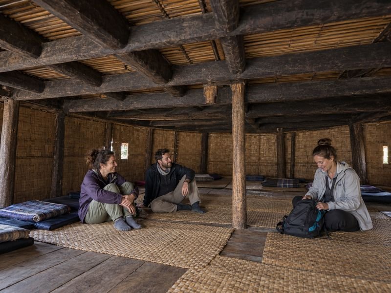 tourists share a living space inside a traditional Wae Rebo house